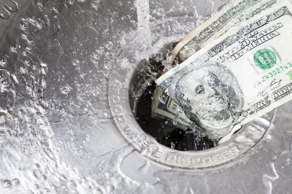 Hundred-dollar bills being washed down a drain.