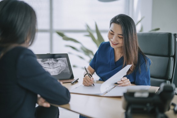 A dentist reviews a patient's X-ray at their desk.