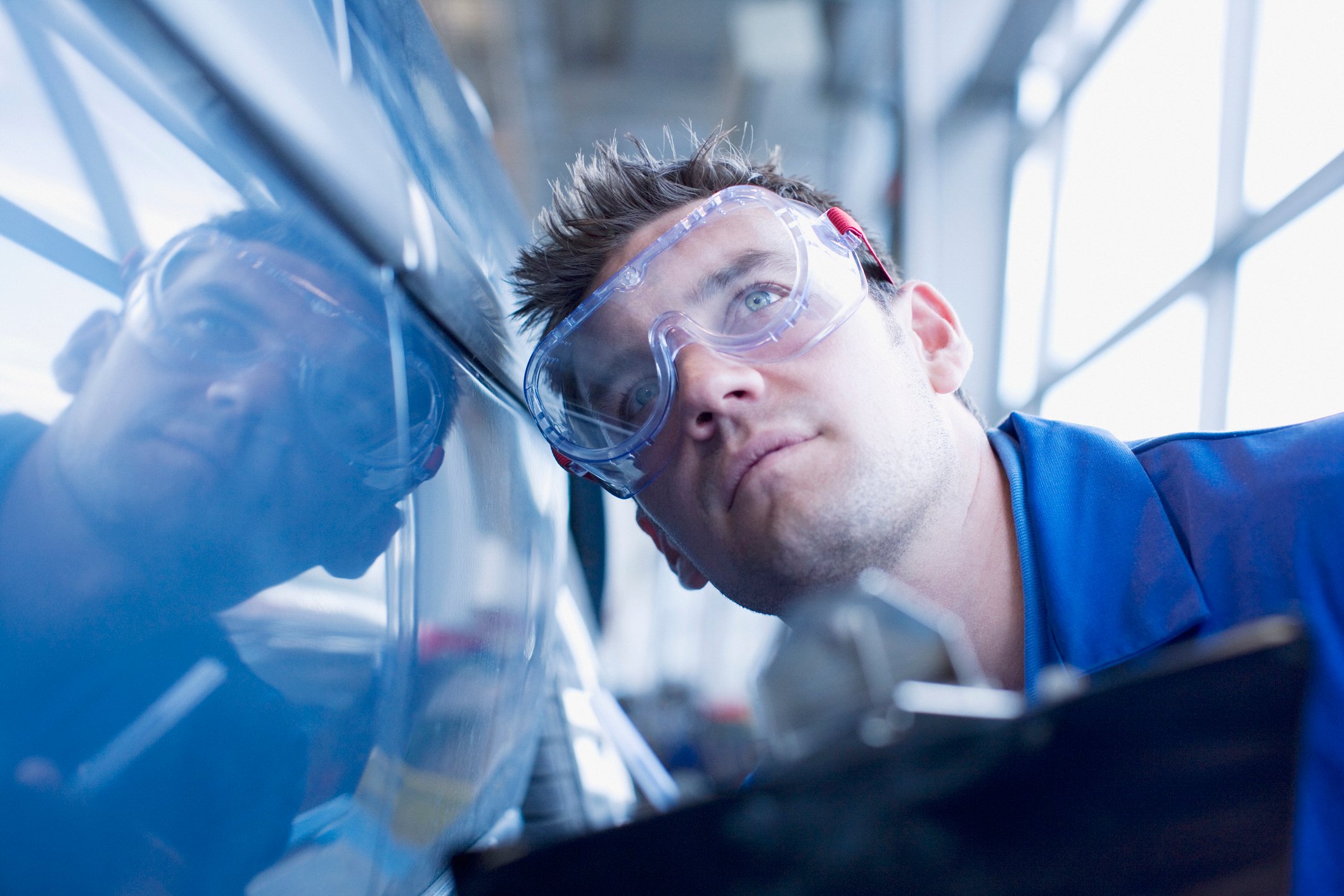 Factory worker inspecting car.