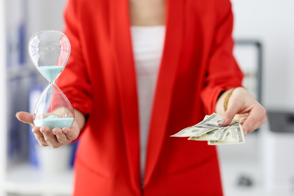 Business person holding money and an hour glass.