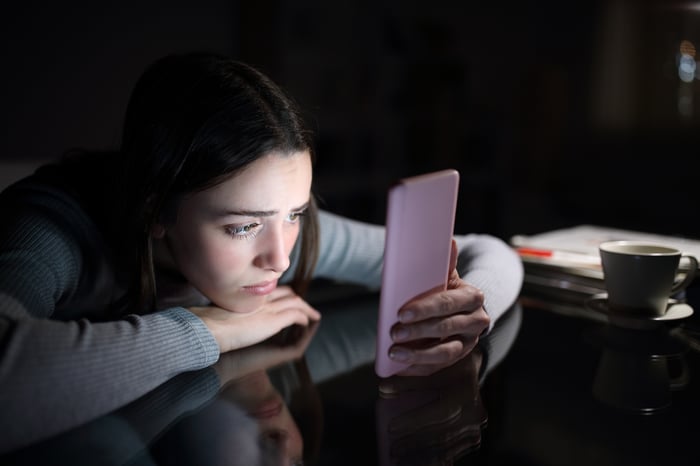 Worried young woman gazing at a smartphone.