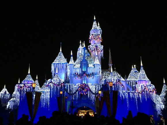 The Sleeping Beauty Castle at Disneyland lit up at night and decorated for the winter.