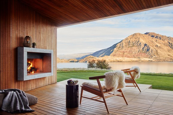 A mountainside veranda featuring a fireplace and two chairs.
