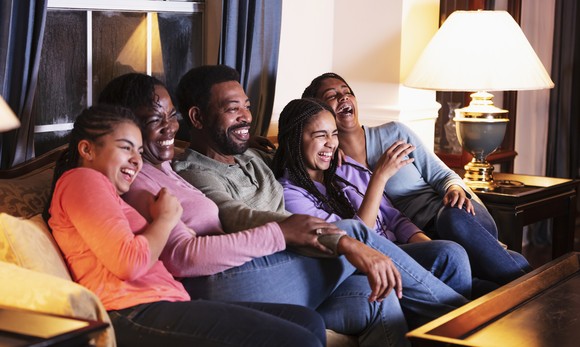 Family and friends laughing at the TV together.