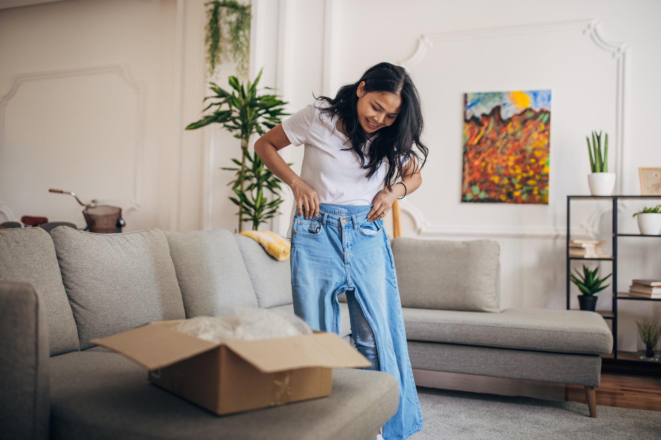 A woman tries out jeans that she purchased online.