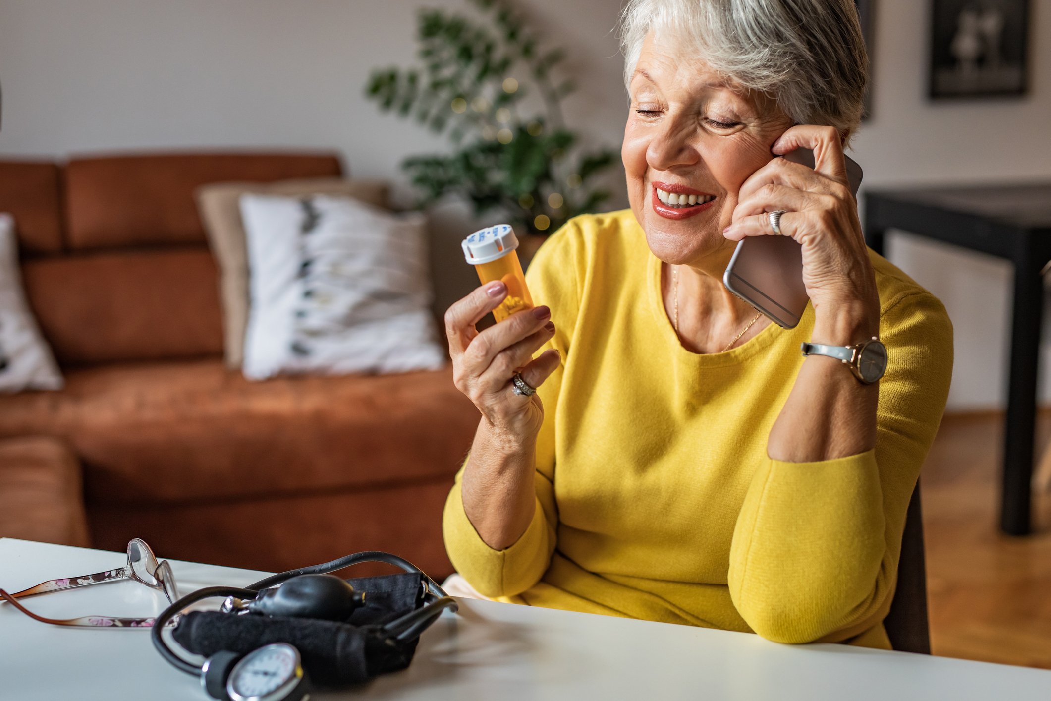 A person holding a prescription bottle and talking on a phone.