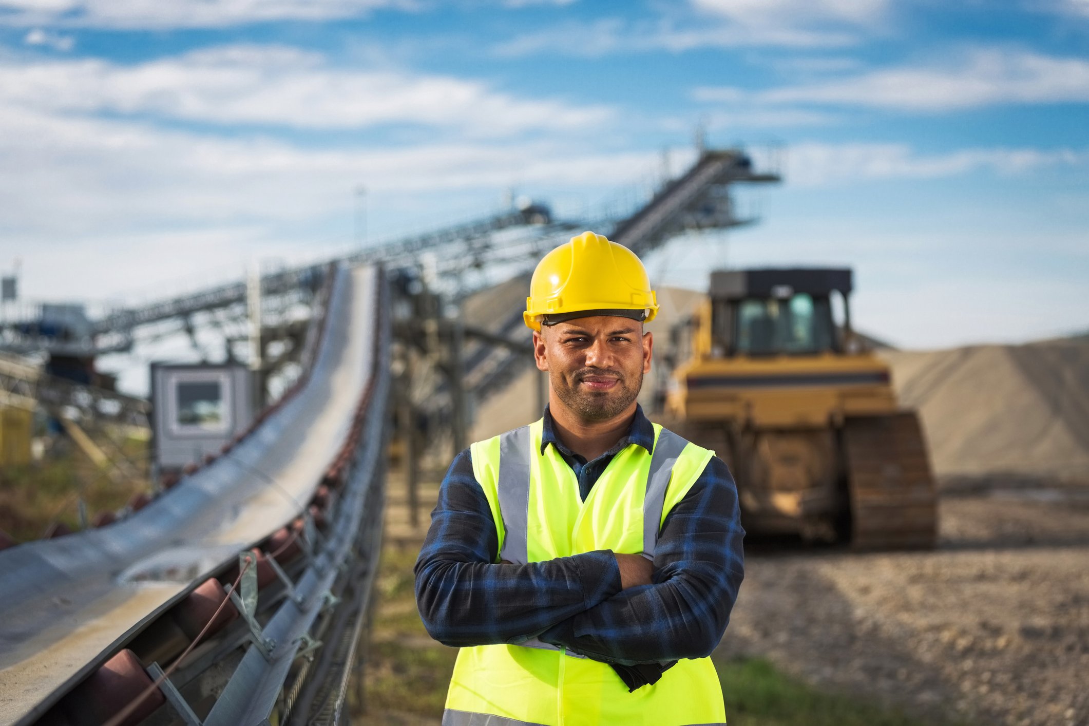 A mining worker looks into the camera with equipment behind him. 