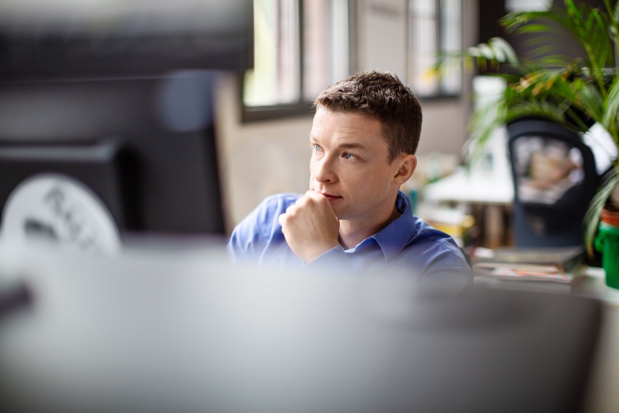 Person in front of a computer looking pensively into the distance.