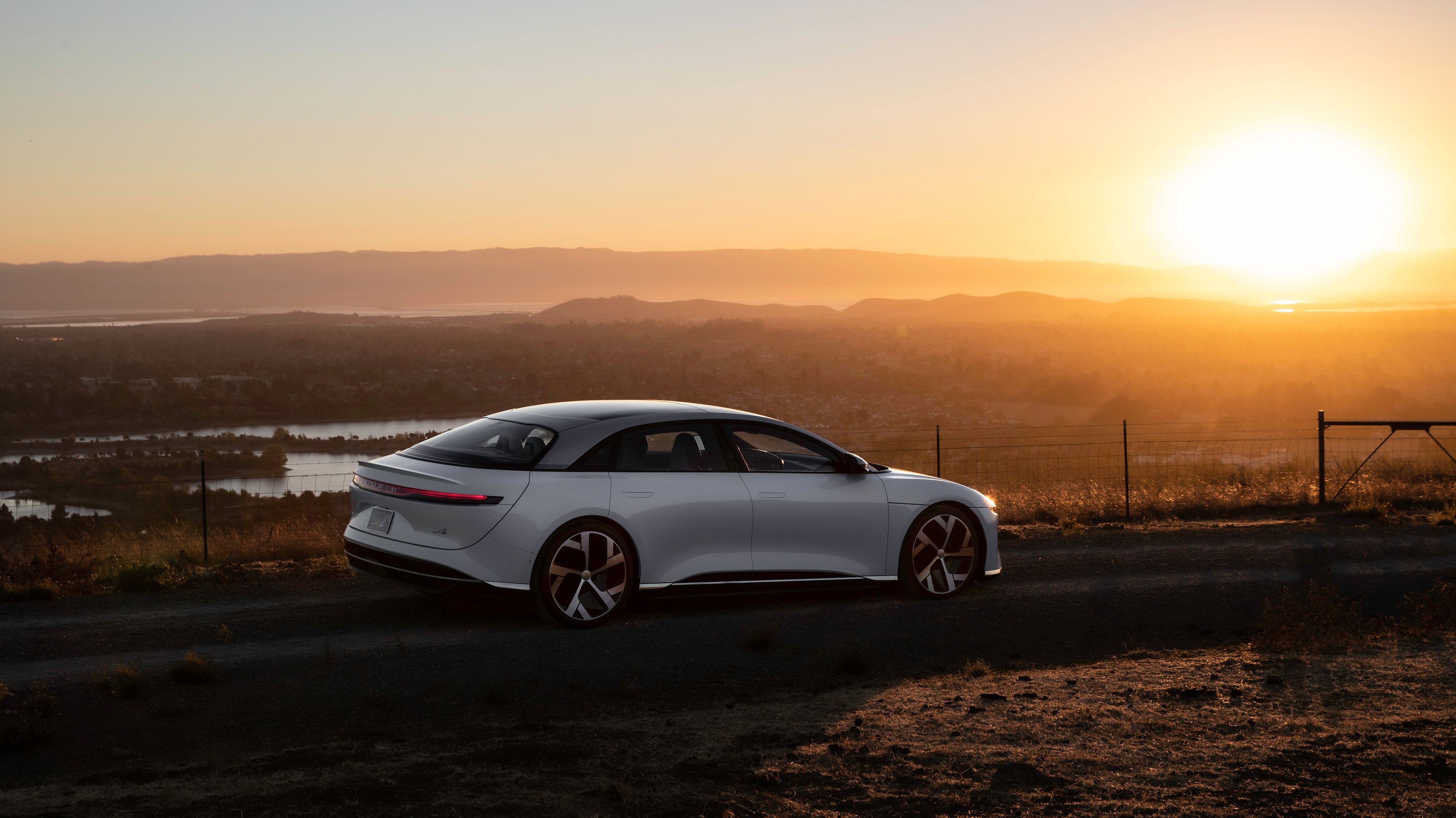 A white Lucid Air sedan at sunrise.