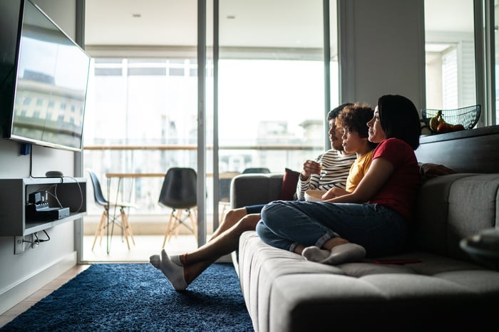 Several people on a couch watching television.