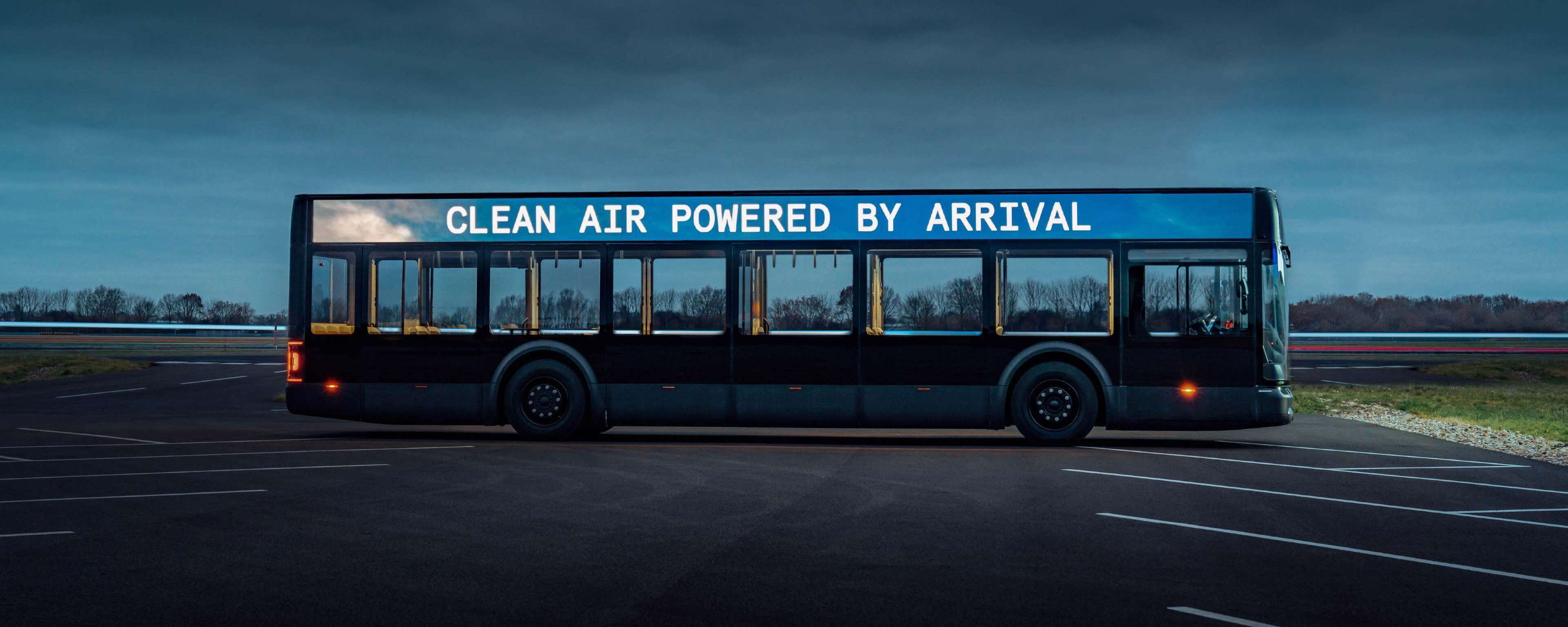 Arrival electric bus with sign saying Clean Air Powered by Arrival in a parking area.