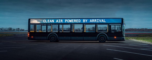 Arrival electric bus with sign saying Clean Air Powered by Arrival in a parking area.