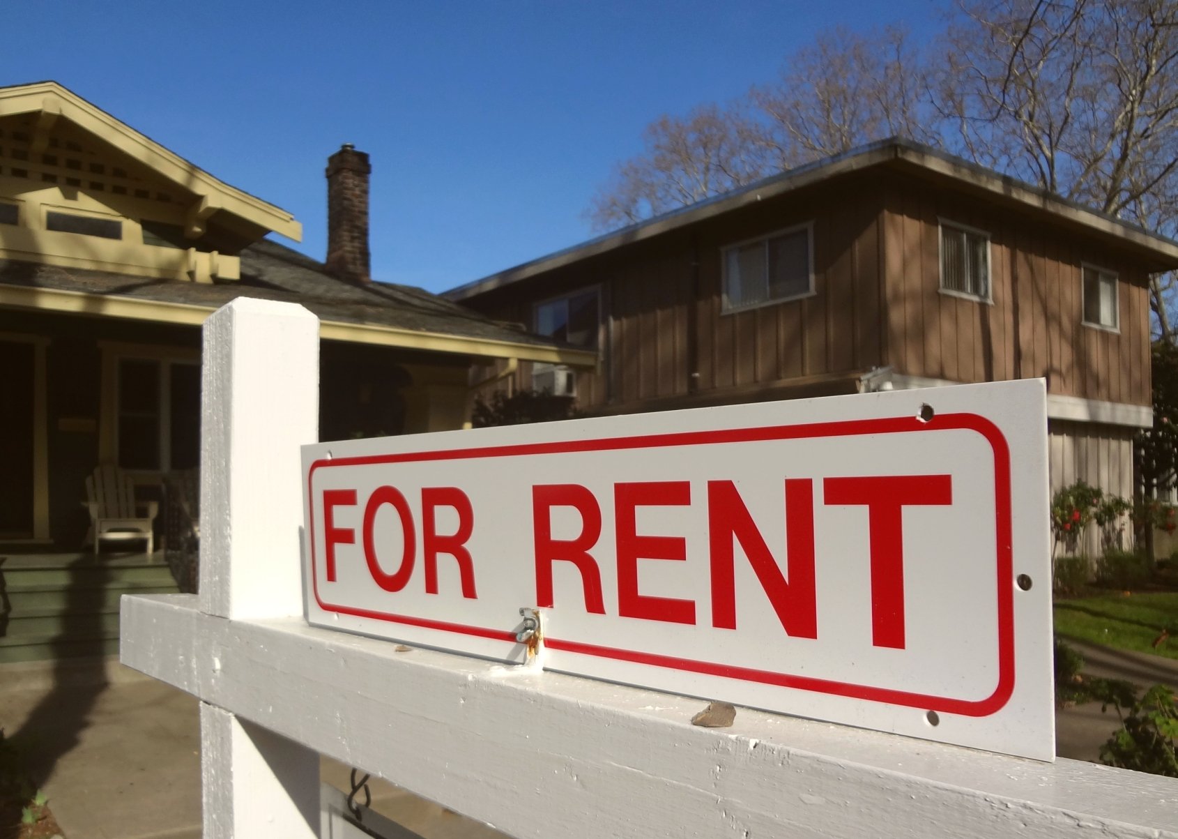 Single-family home with for rent sign in front yard.