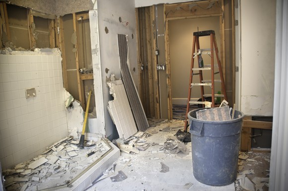 Bathroom under renovation with debris and ladder.