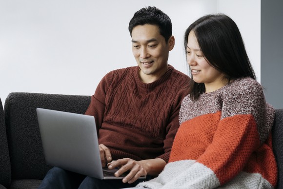 Two smiling people looking at a laptop.