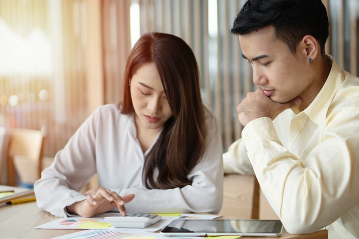 Two people sitting at table looking at financial paperwork. 