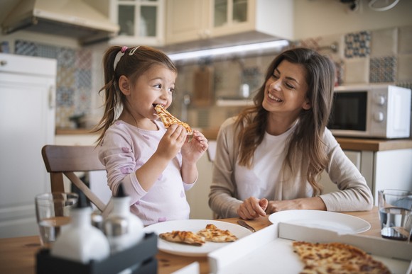 Adult and child eating pizza at home.