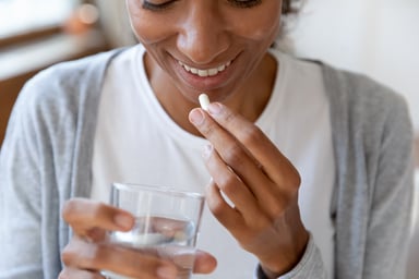 woman takes pill while smiling