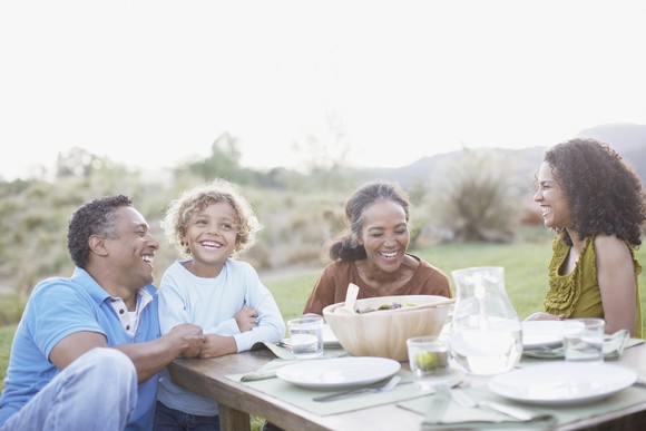 Group of young and old people dining outdoors.