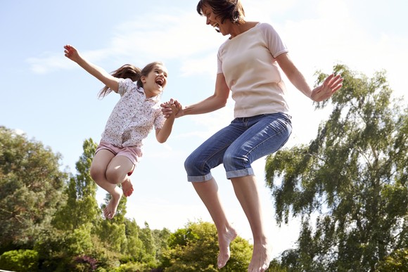 Adult and child bouncing on a trampoline.