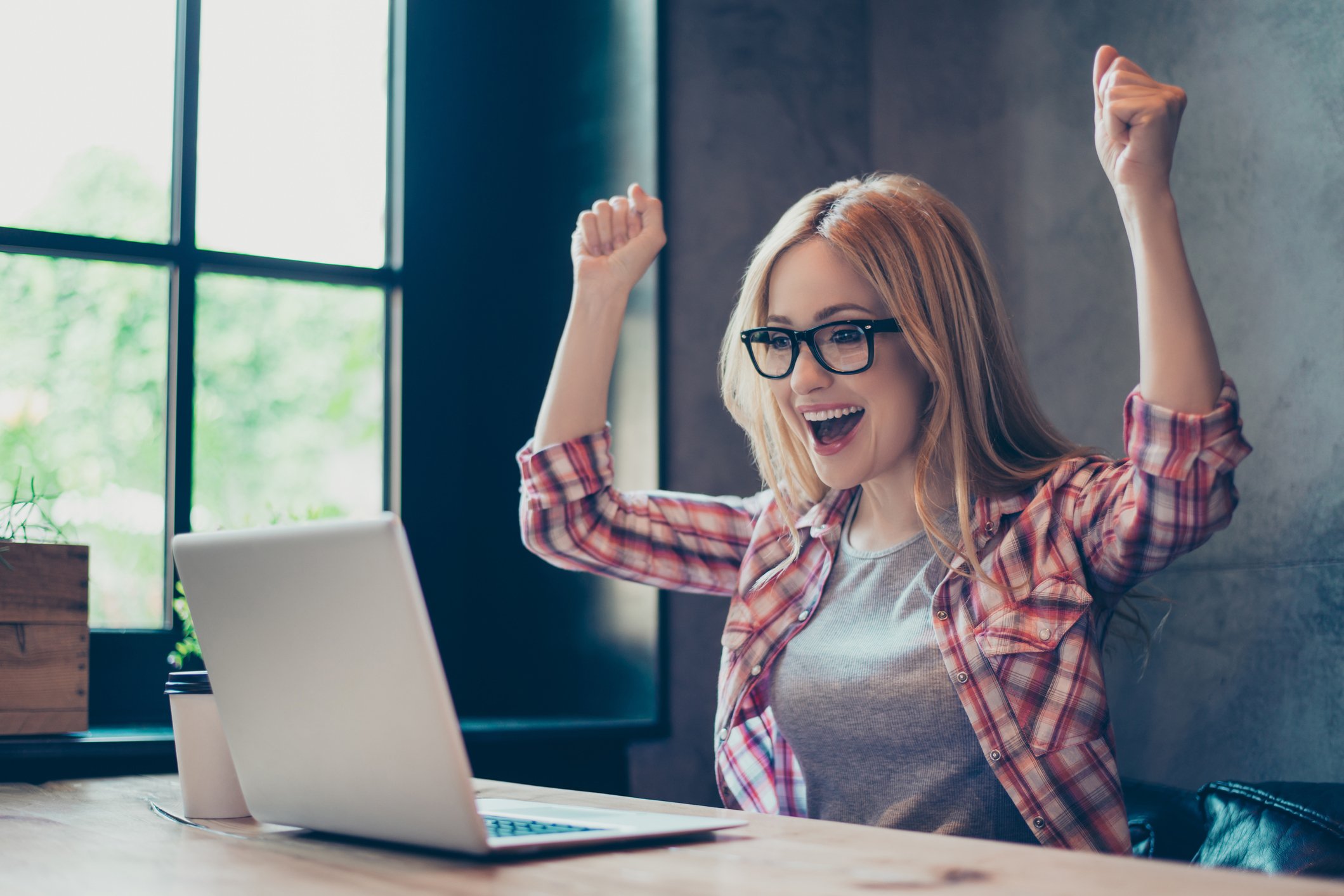 A person cheering in front of a laptop computer.
