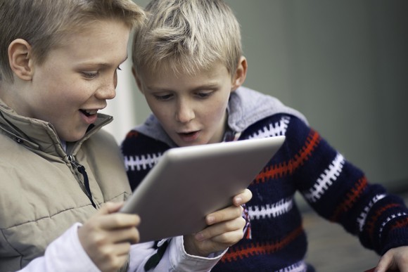 Two kids playing a game on a tablet.