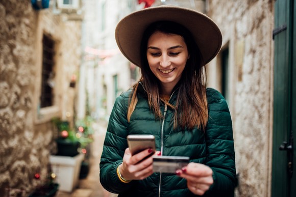Person holding credit card and smartphone in an alley.