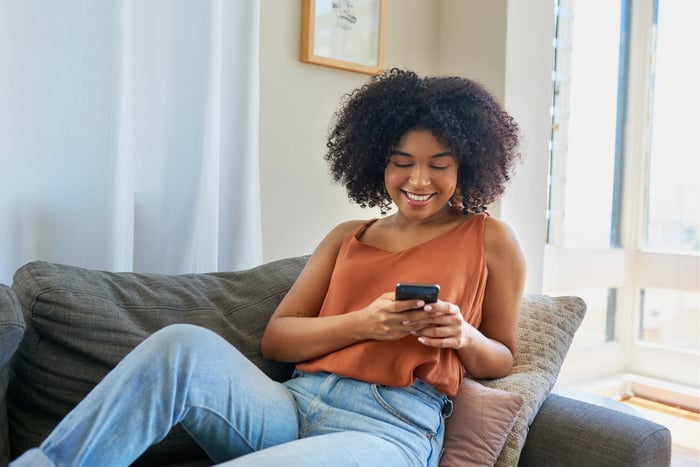 Person sitting on a couch holding a smartphone. 