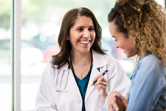 A happy healthcare professional conferring with a young woman.
