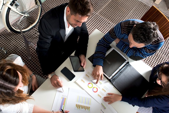 Group of investors analyzing charts while seated around a table.