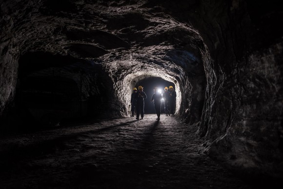 A group of miners walk through an underground mine.