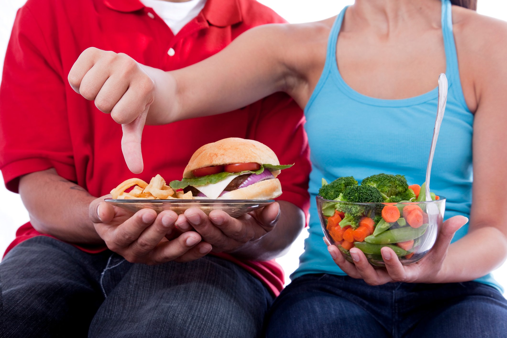 Torsos of two people with food items, with the woman showing a thumbs down above a plate with a burger.