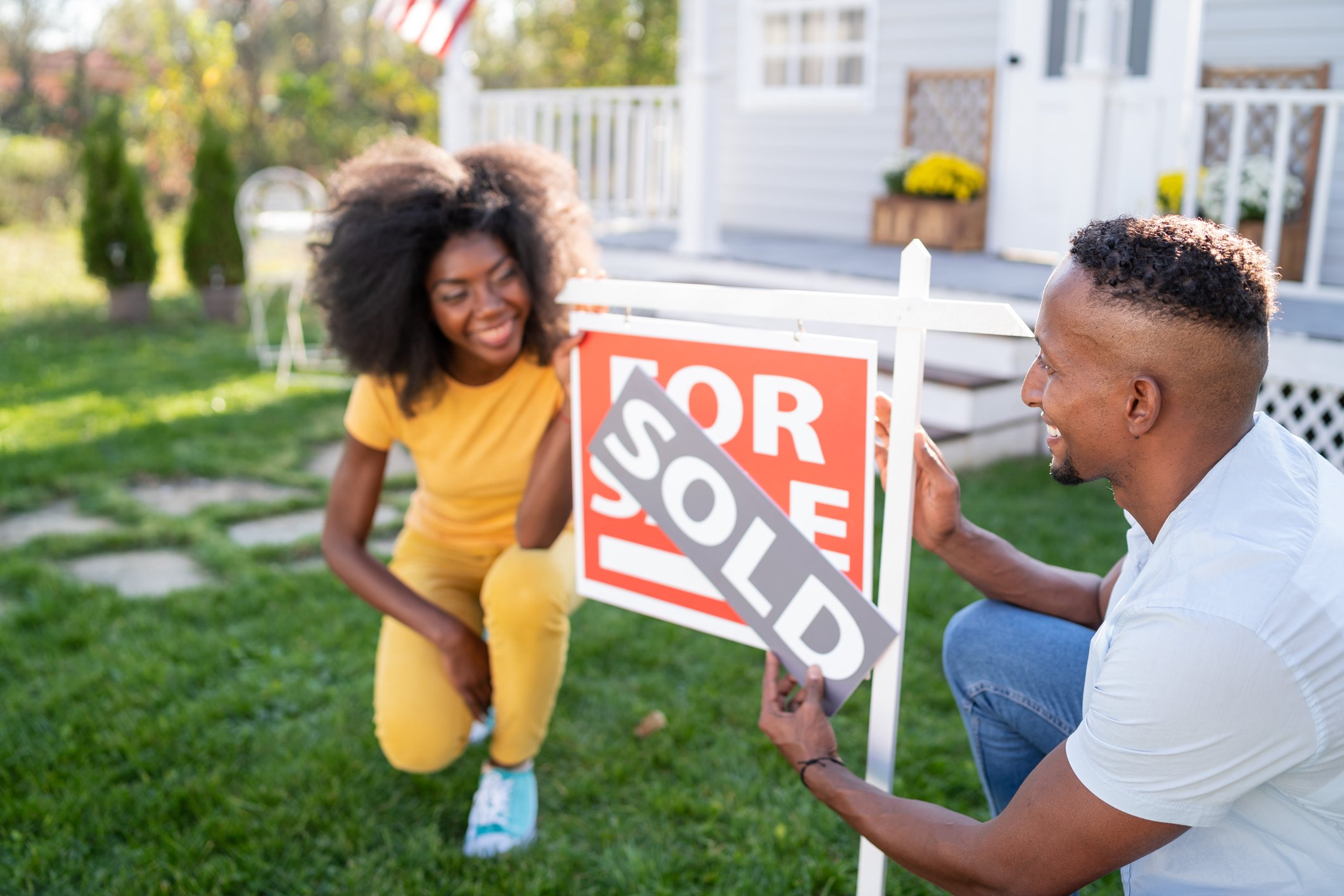 Two people looking at a sold sign.