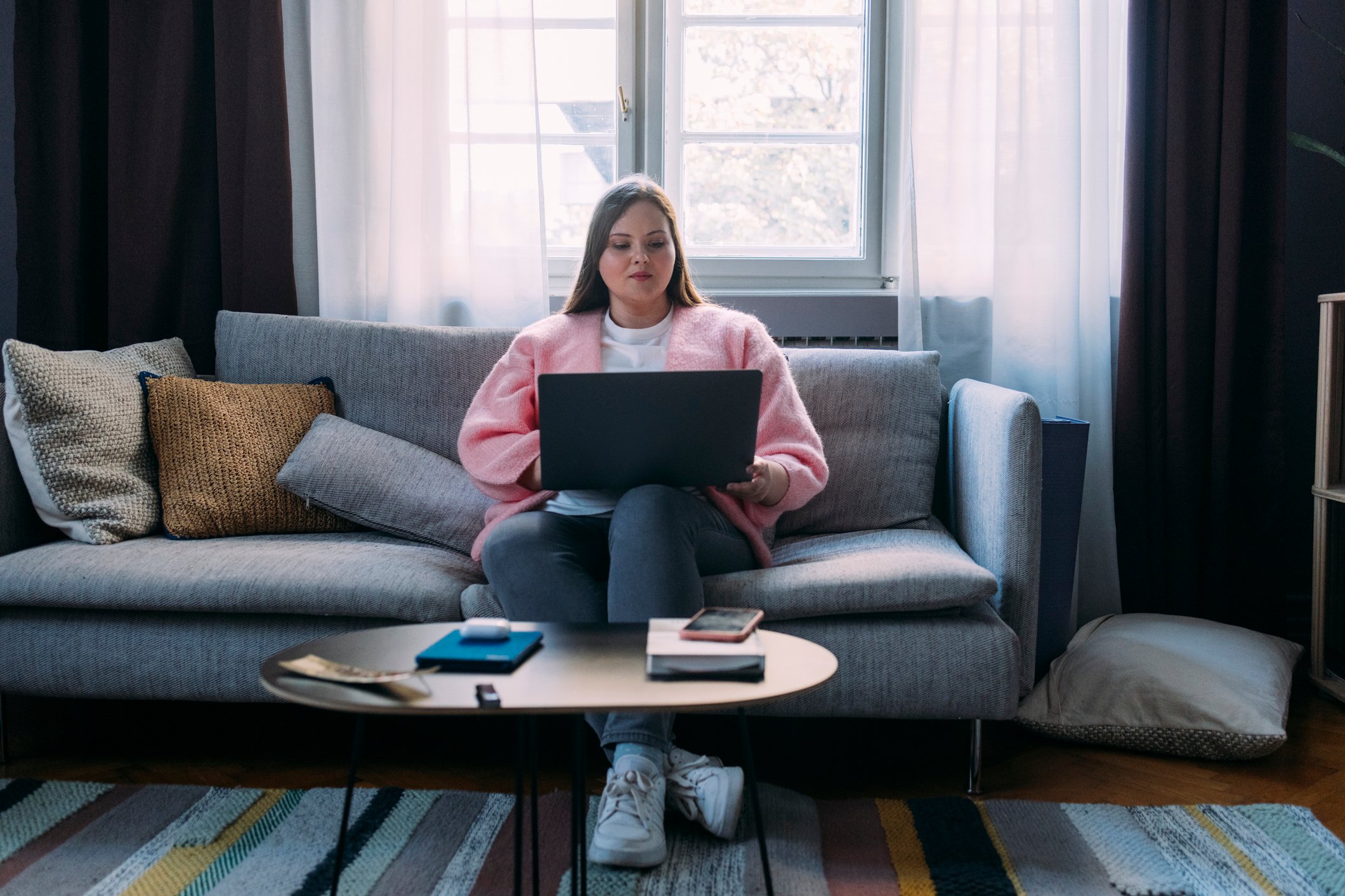 Woman sitting on a couch and working on a laptop computer.