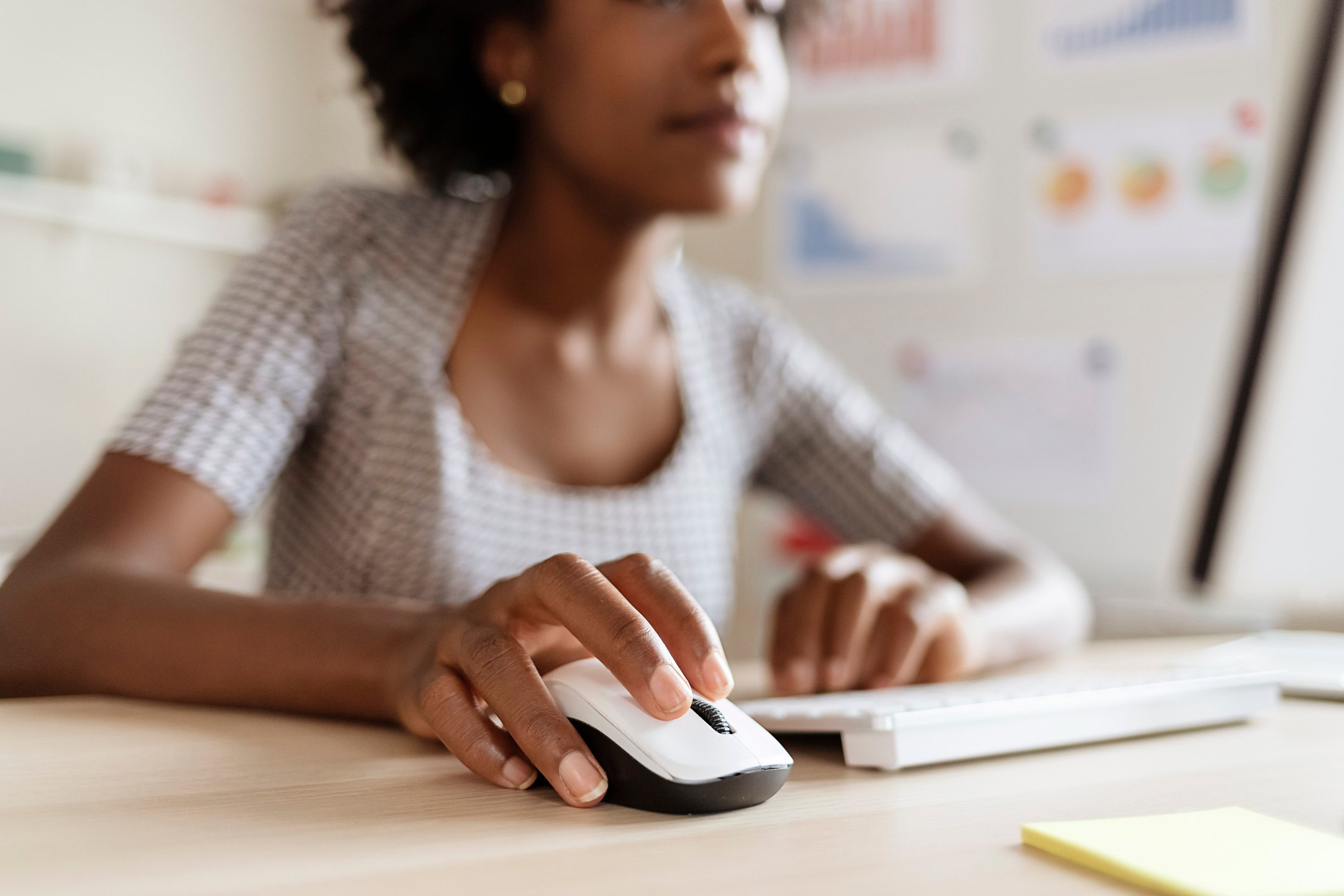 A remote worker holding a computer mouse on a desk.