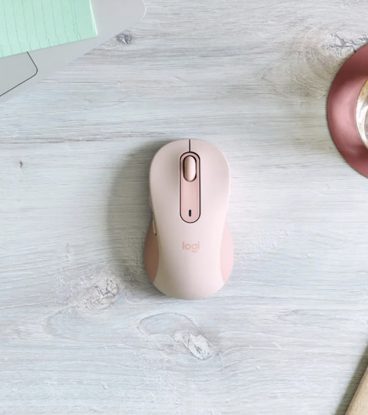A soft pink-colored computer mouse on a desk.