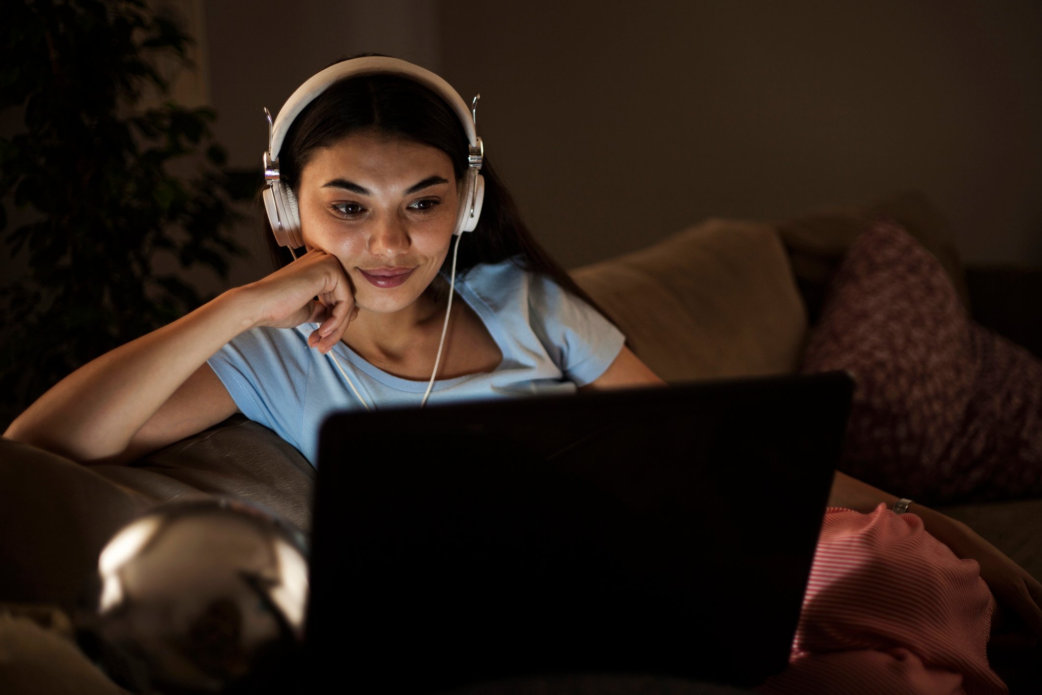 Woman wearing headphones while watching content on her computer.