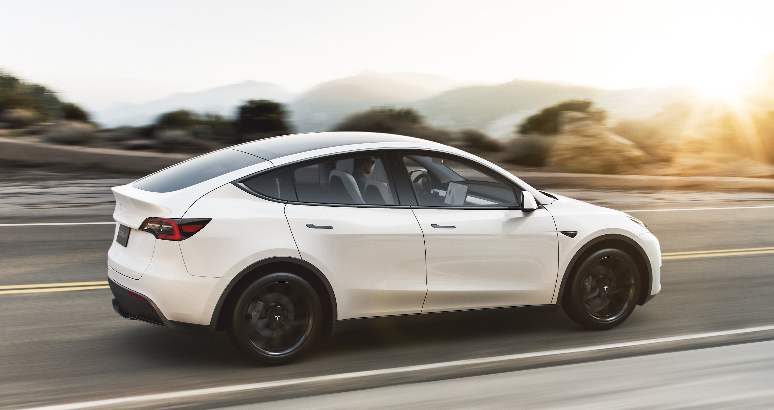 A white Tesla Model Y, a compact electric luxury crossover SUV.