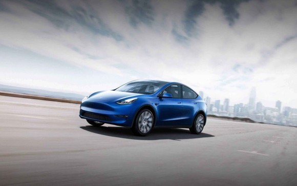A blue Tesla Model Y cruises down an open road.