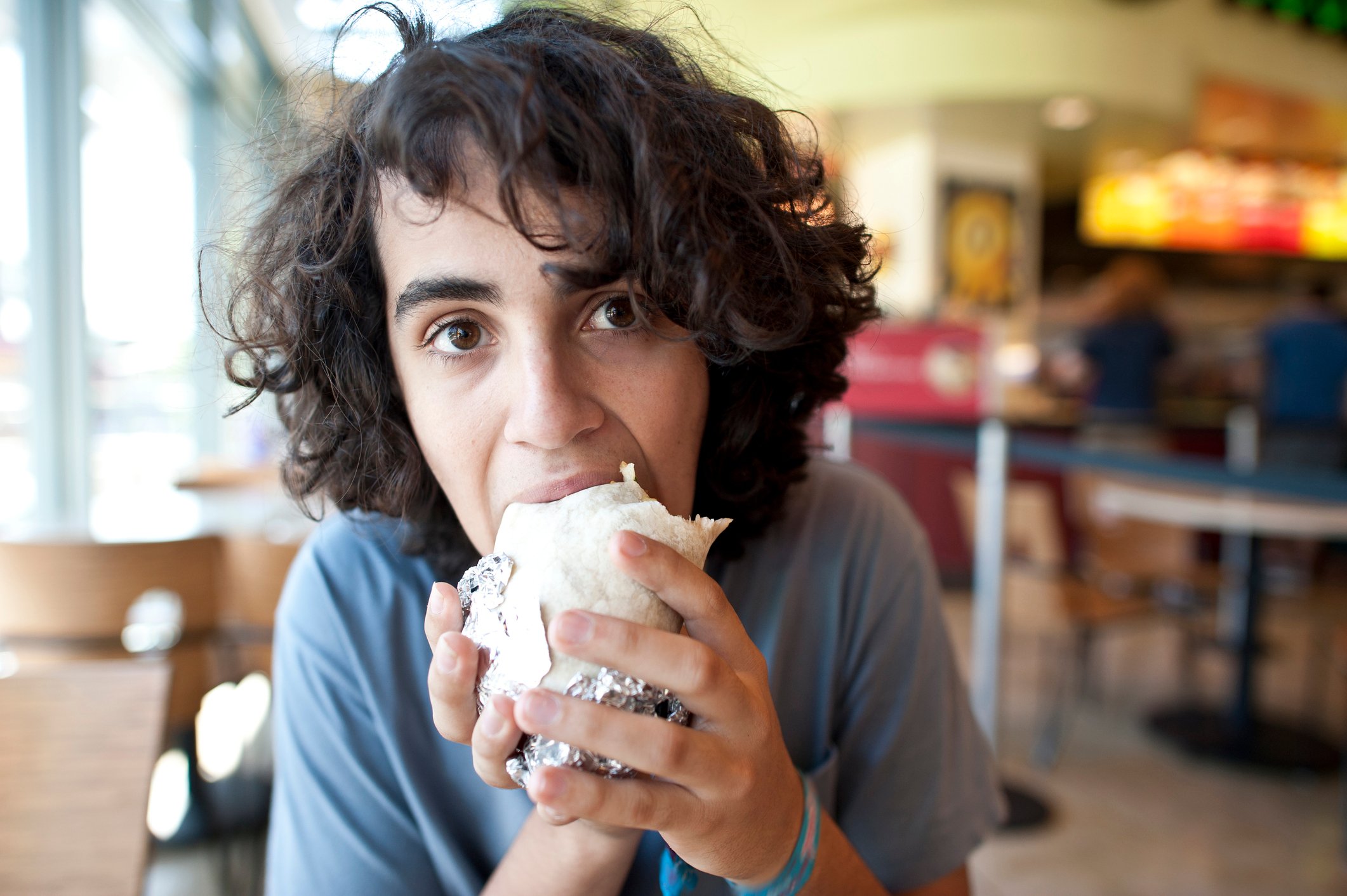 Person eating a fresh burrito.