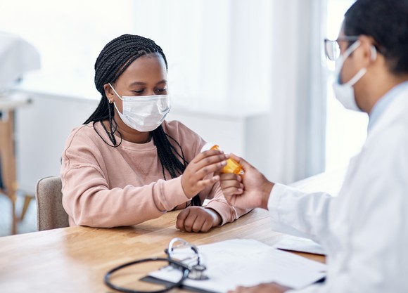 A doctor handing a patient a bottle of medicine.