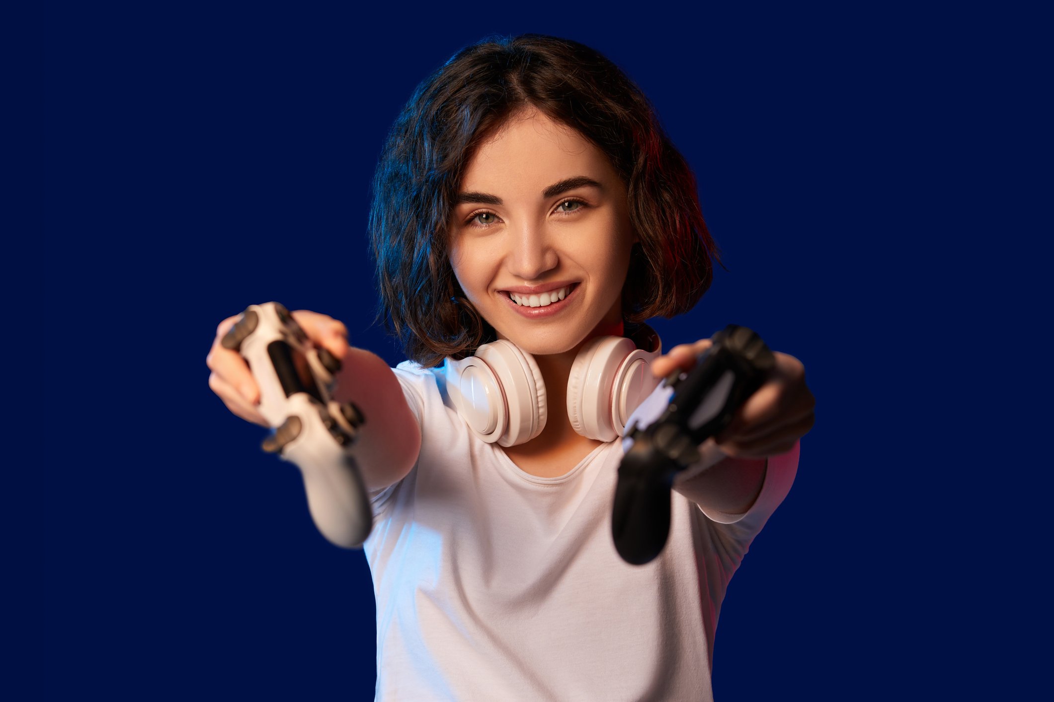 A happy gamer holds up two video game controllers.