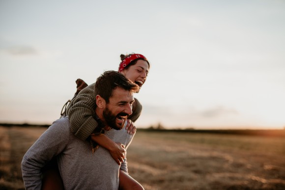 Two people smiling outside, with one person being carried on the other person's back.