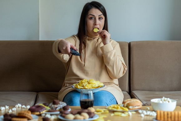 Person having soda and chips on a couch.