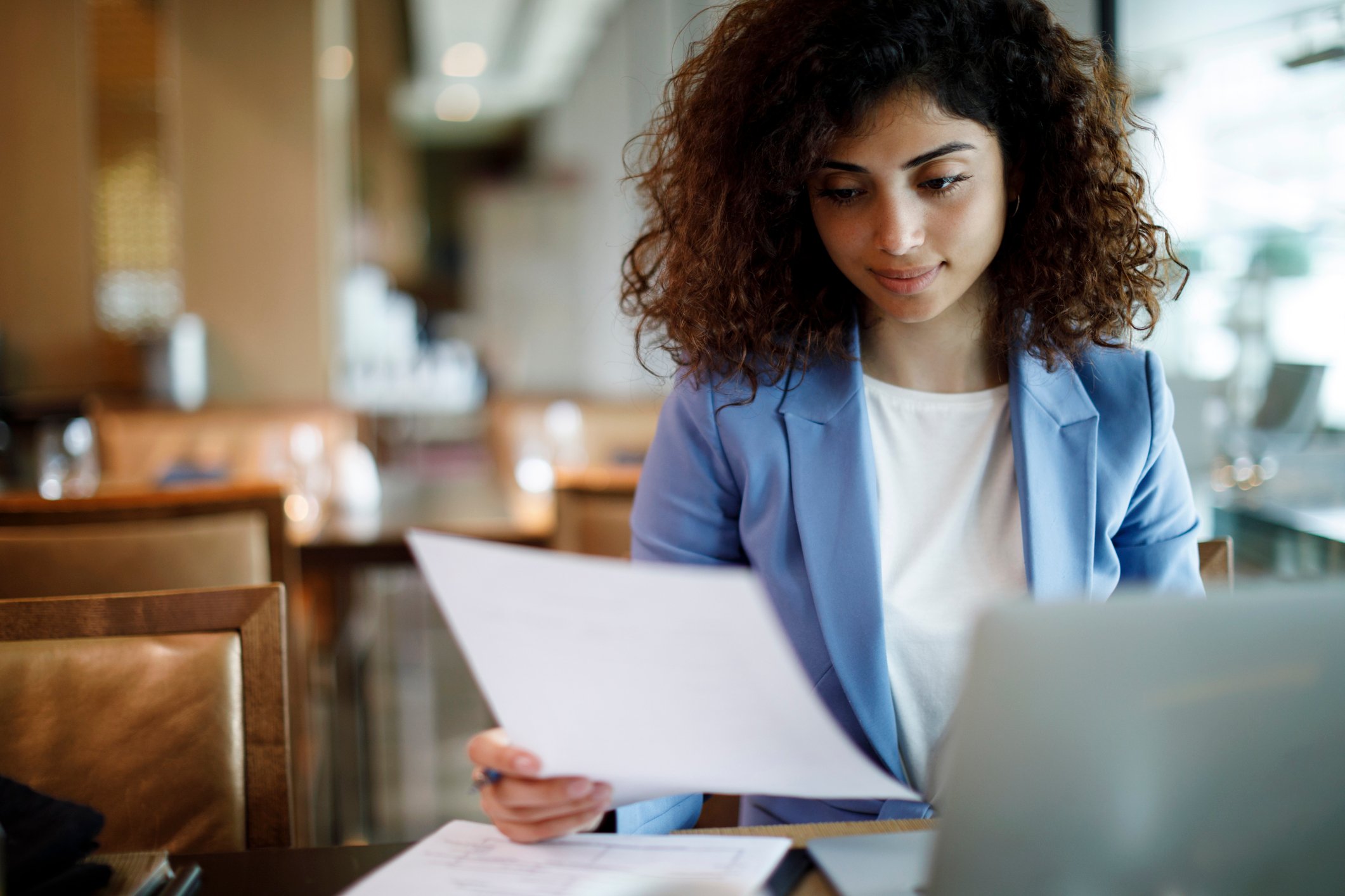 Businesswoman reading a document while sitting at her computer.