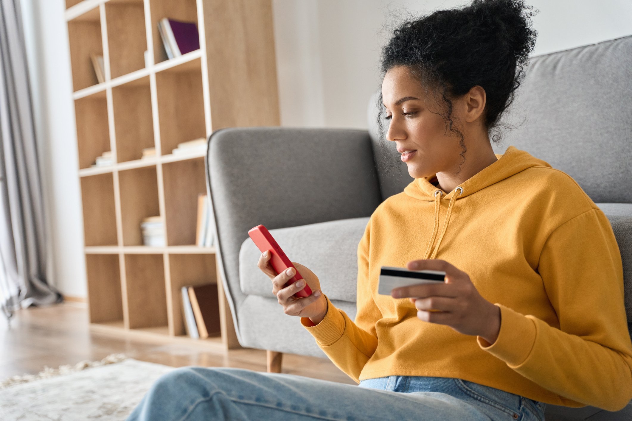 Woman holding credit card in one hand and phone in the other.