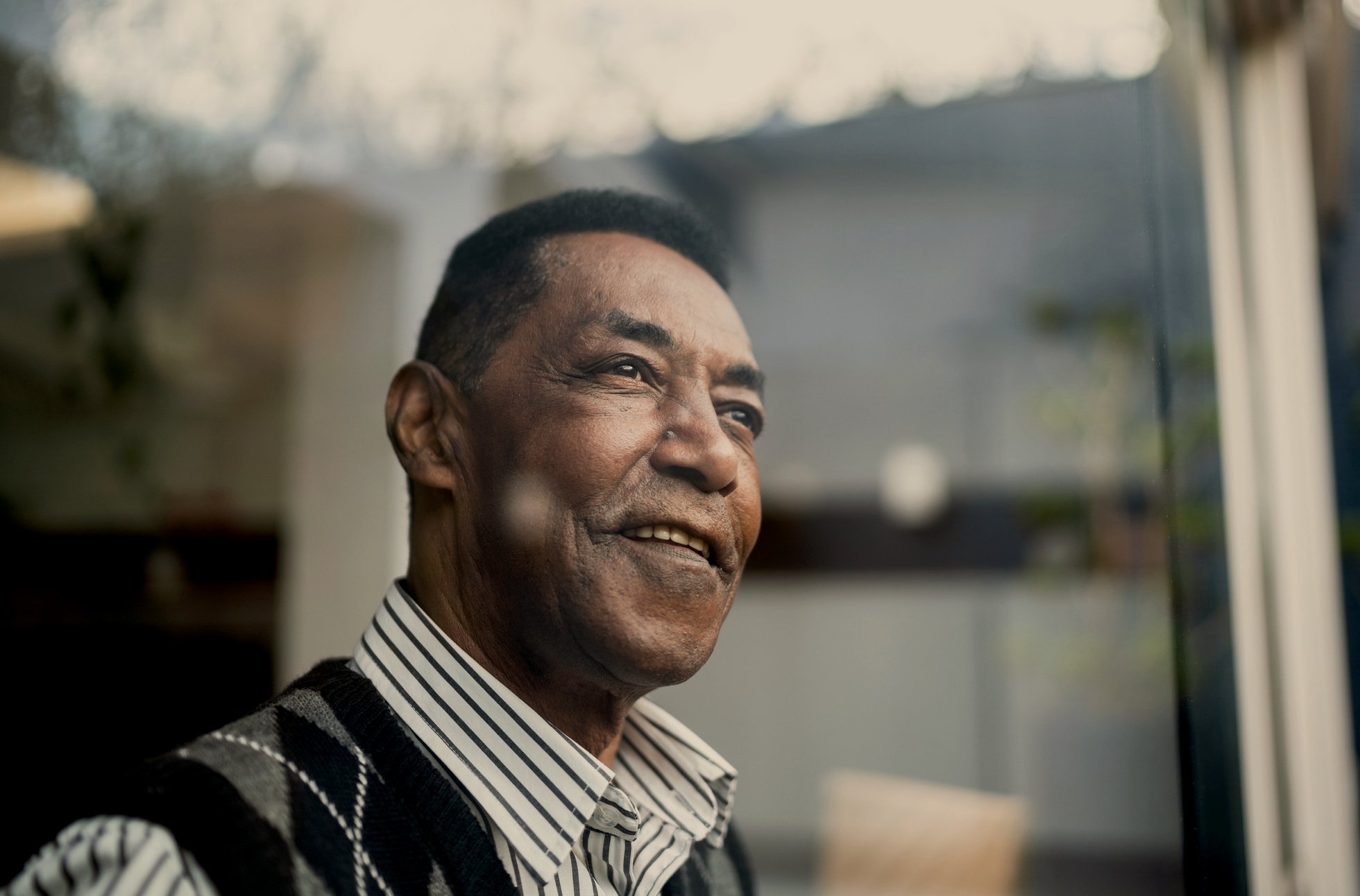 A person smirks while looking out through a large window.