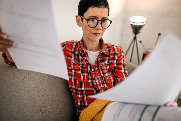 A person looks at documents while sitting on a couch.