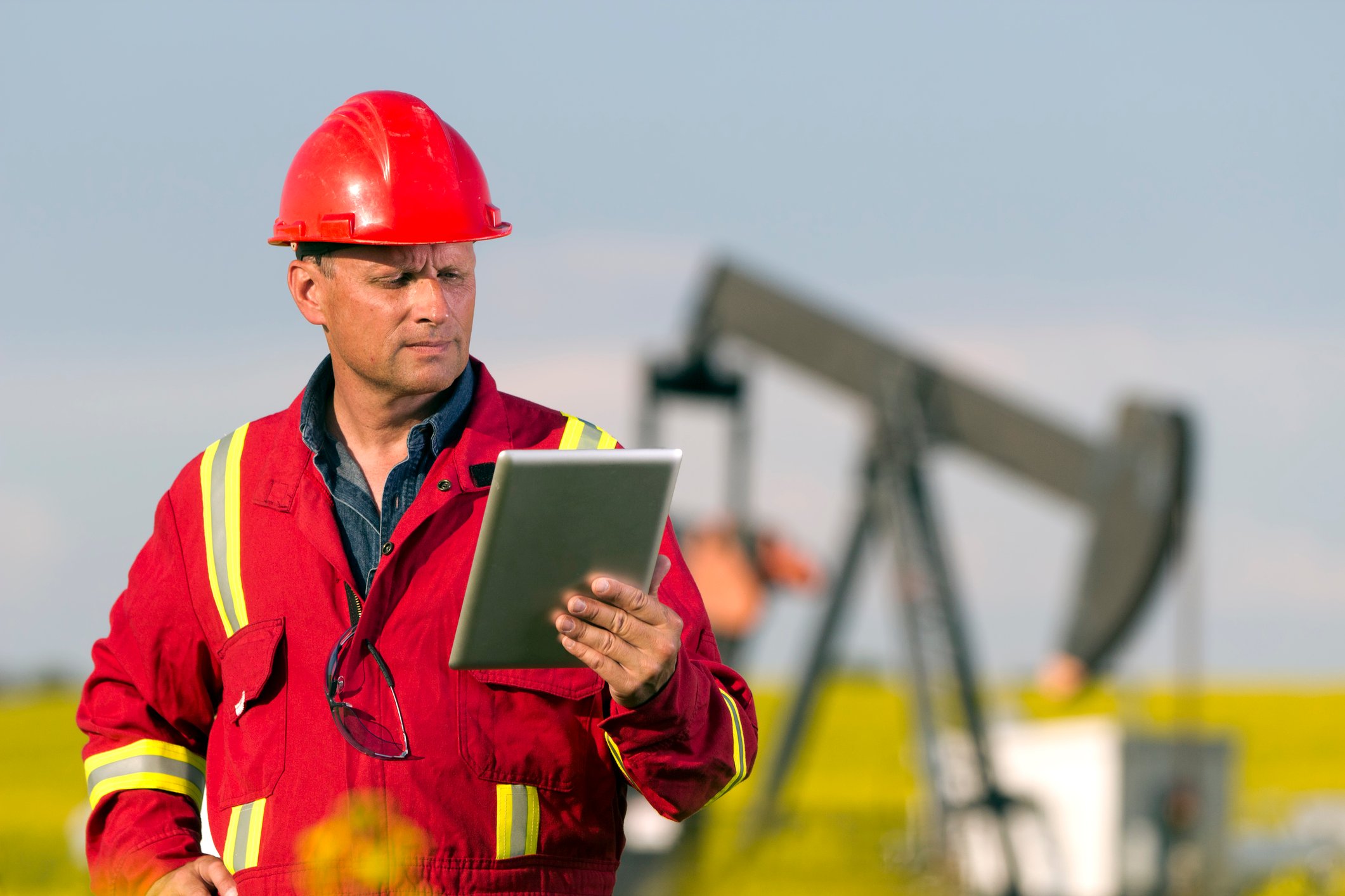 Oil well operating using a tablet to monitor progress.