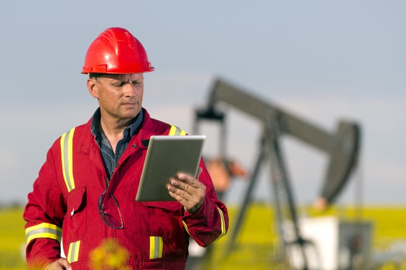 Oil well operating using a tablet to monitor progress.